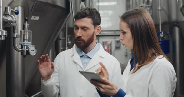 남성 과 여성의 처리 과정은 장비 게이지와 대화를 보는 유전학 자들 이다. 흰색 실험실에 있는 남녀가 자동 음료 머신 가까이 서 있는 동안 자료를 입력하고 태블릿을 사용하는 모습. — 비디오