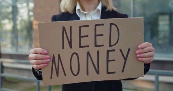 Crop kilátás a női munkavállaló mutatja karton banner szükség pénz írás. Üzletasszony pénzügyi problémákkal, miközben az utcán áll. A pénzügyi válság és a munkanélküliség fogalma. — Stock videók