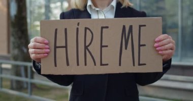 Kadın işçinin karton pankartı göstermesi beni yazı yazarken işe aldı. Sokakta dikilirken iş arayan bir kadın. Küresel mali kriz ve işsizlik kavramı.