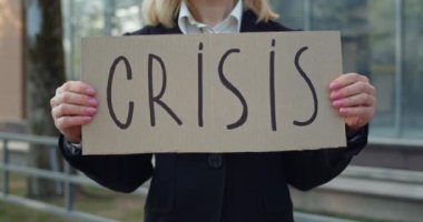 Kadın işçinin karton pankartı kriz yazısıyla göstermesi. Görevden alındıktan sonra sokakta duran takım elbiseli işsiz kadın. Küresel mali kriz ve işsizlik kavramı.