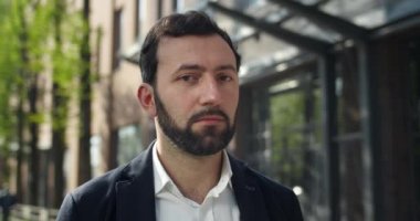 30 'lu yaşlarda kameraya bakan ciddi bir erkek portresi. Sokakta dikilirken resmi giyinen kendine güvenen işadamlarına yakından bakın. İş ve iş kavramı.