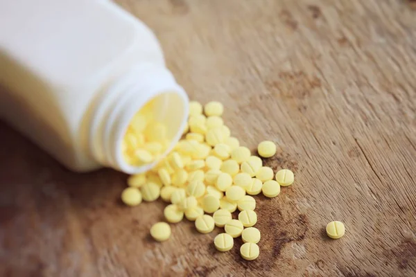 Yellow pills on wood