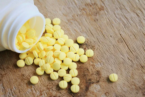 Yellow pills on wood