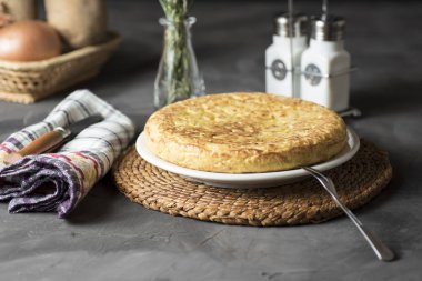 İspanyol patates omleti, masada, pişirilmesi gereken ve yenmeye hazır malzemelerin yanında.
