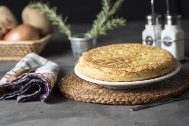 İspanyol patates omleti, masada, pişirilmesi gereken ve yenmeye hazır malzemelerin yanında.