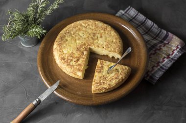 İspanyol patates omleti, masada, pişirilmesi gereken ve yenmeye hazır malzemelerin yanında.