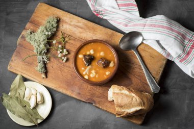 Tahta bir tahtanın üzerinde kil bir tencerede nasırlı nohut, defne ekmeği ve süs ile