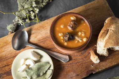 Tahta bir tahtanın üzerinde kil bir tencerede nasırlı nohut, defne ekmeği ve süs ile