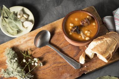 Tahta bir tahtanın üzerinde kil bir tencerede nasırlı nohut, defne ekmeği ve süs ile