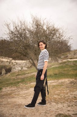 Arkadaki ağaçla tarlada poz veren genç bir adam. Tadını çıkarıyorum.