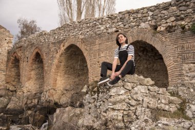 Tarlada poz veren ve arka planda köprüsü olan genç bir adam. Açık havanın tadını çıkarıyorum.