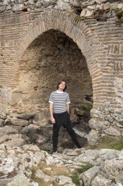 Tarlada poz veren ve arka planda köprüsü olan genç bir adam. Açık havanın tadını çıkarıyorum.