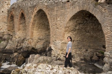 Tarlada poz veren ve arka planda köprüsü olan genç bir adam. Açık havanın tadını çıkarıyorum.