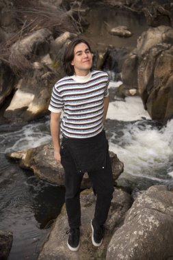 Tarlada poz veren ve arka planda köprüsü olan genç bir adam. Açık havanın tadını çıkarıyorum.