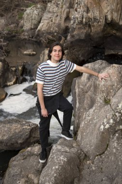 Tarlada poz veren ve arka planda köprüsü olan genç bir adam. Açık havanın tadını çıkarıyorum.