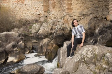 Tarlada poz veren ve arka planda köprüsü olan genç bir adam. Açık havanın tadını çıkarıyorum.