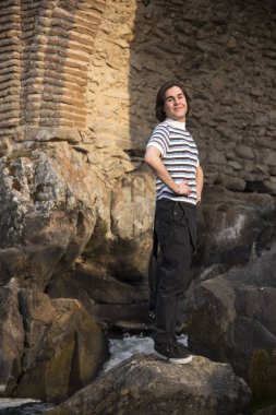 Tarlada poz veren ve arka planda köprüsü olan genç bir adam. Açık havanın tadını çıkarıyorum.