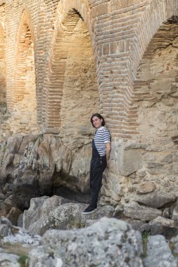 Tarlada poz veren ve arka planda köprüsü olan genç bir adam. Açık havanın tadını çıkarıyorum.