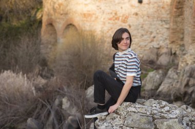 Tarlada poz veren ve arka planda köprüsü olan genç bir adam. Açık havanın tadını çıkarıyorum.