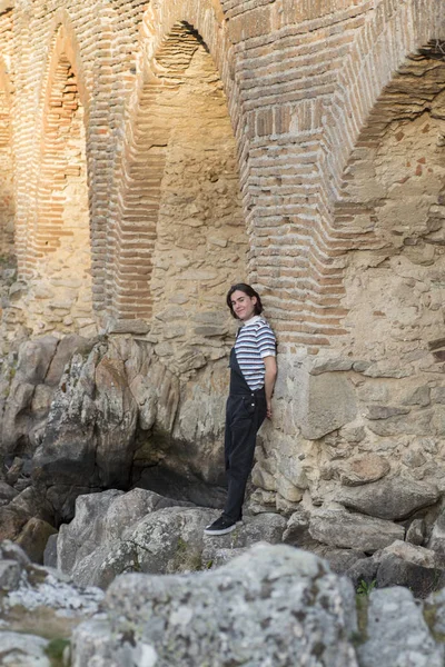 Tarlada poz veren ve arka planda köprüsü olan genç bir adam. Açık havanın tadını çıkarıyorum.