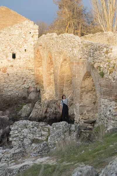 Tarlada poz veren ve arka planda köprüsü olan genç bir adam. Açık havanın tadını çıkarıyorum.