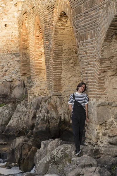 Tarlada poz veren ve arka planda köprüsü olan genç bir adam. Açık havanın tadını çıkarıyorum.