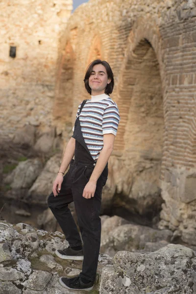 Tarlada poz veren ve arka planda köprüsü olan genç bir adam. Açık havanın tadını çıkarıyorum.