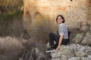 Tarlada poz veren ve arka planda köprüsü olan genç bir adam. Açık havanın tadını çıkarıyorum.