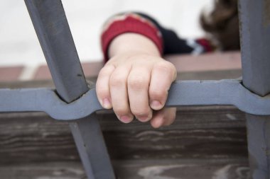 Gülümseyen küçük çocuk demir bir çitin arkasında kilitli.