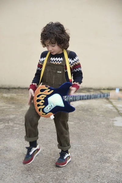 Boy playing and experimenting with a toy guitar with striking co — 스톡 사진