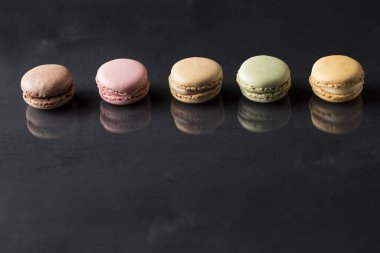 Siyah bir yüzeyde renkli makaronlar ve bir yansıması var.