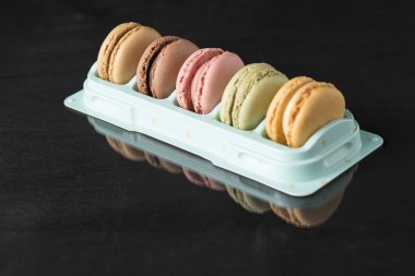 Siyah bir yüzeyde renkli makaronlar ve bir yansıması var.