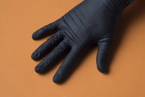 Black Sanitary Glove Placed Hand Orange Background — Stock Photo, Image