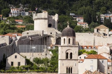 Şehrin üst kesimindeki Dubrovnik, Hırvatistan ve Avrupa 'daki bir sokaktan kırmızı kiremit çatılar, bir kule ve taş duvarın bir kısmı görünüyor..