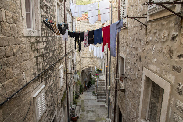 Narrow street on slope with stone stairs and clothes hanging in Dubrovnik, Croatia, Europe.