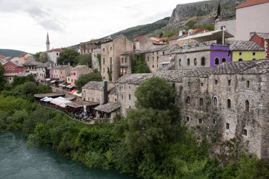 Bosna-Avrupa 'daki Neretva Nehri kıyısında renkli cepheli ve çatılı Mostar manzarası.
