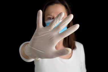 Kısmen koruyucu maske taktığı yüzü, tek eliyle, siyah bir arka planda lateks eldivenle kapattığı için affedin. Bulaşıcı hastalıklara karşı koruma.