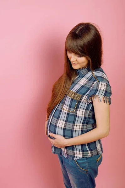Mulher grávida em jeans e camisa xadrez segurando sua barriga — Fotografia de Stock