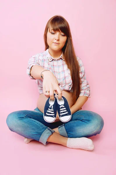 Zwangere vrouw in jeans en geruite overhemd zitten cross benen — Stockfoto