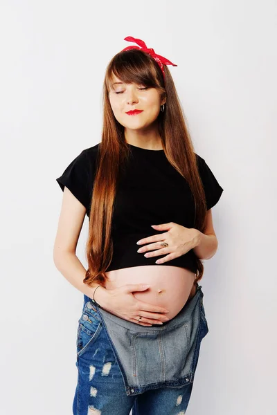 Беременная женщина в черной футболке и джинсовом комбинезоне — стоковое фото