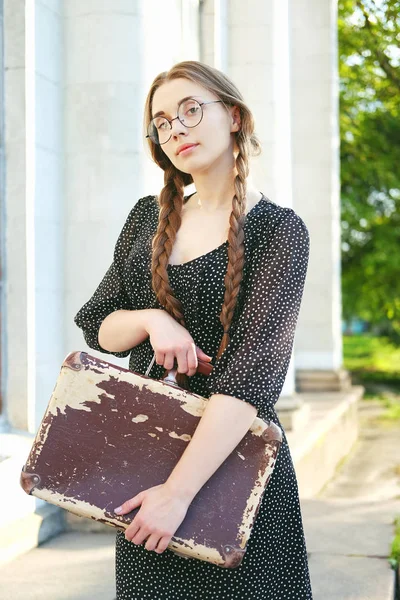 Молодая студентка с чемоданом и длинными косичками — стоковое фото