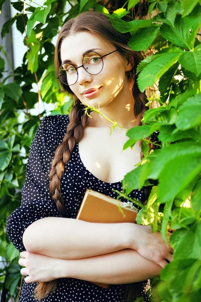 Junge Studentin mit langen Zöpfen und einem Liebesroman — Stockfoto