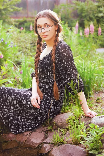 Молодая наивная деревенская девушка с длинными косичками и очками — стоковое фото