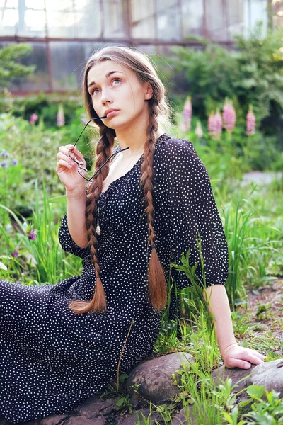 Young naive village girl with long braids and glasses — Stock Photo, Image