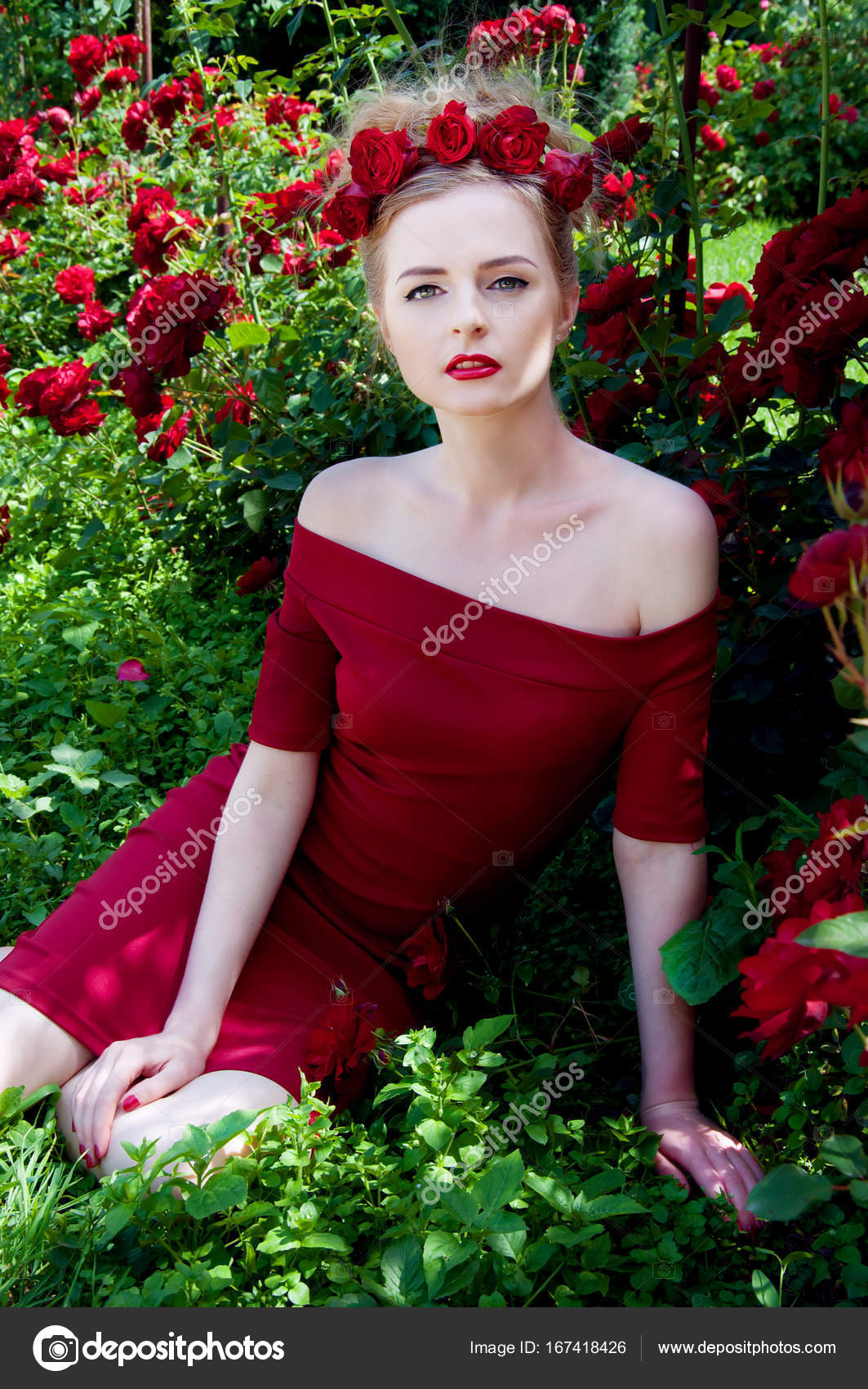Lady vamp in crimson red dress with naked shoulders and red rose