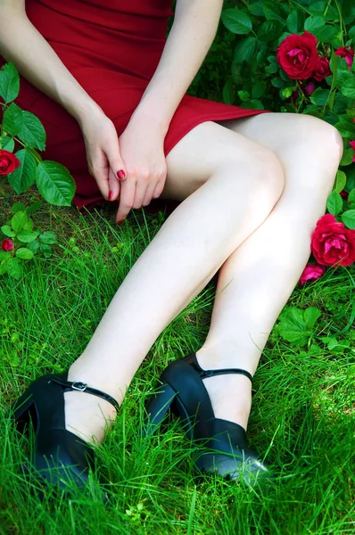 Tajemnicza dziewczyna siedzi na zielonej trawie w czerwonej sukience — Zdjęcie stockowe