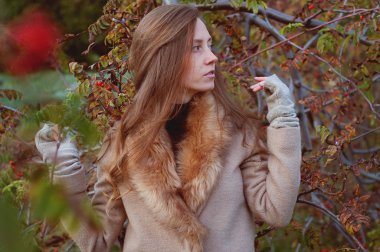 Kürk palto giyiyor rowanberry çalılar arasında şirin Kızıl saçlı kadın