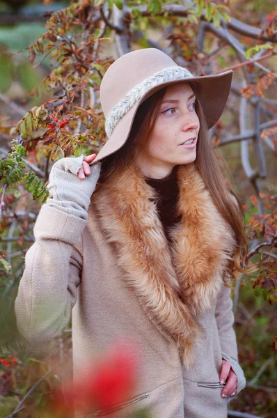 Carino rossa donna tra i cespugli di rowanberry indossa cappello fedora — Foto Stock