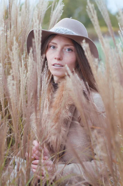 Donna in pelliccia beige nel campo asciutto autunnale — Foto Stock