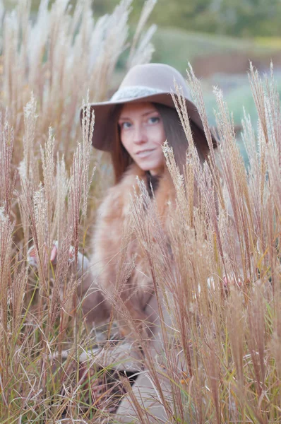 Donna in pelliccia beige nel campo asciutto autunnale, focus selettivo — Foto Stock